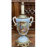 A continental porcelain twin handled lamp decorated with figures seated in a garden to a light blue