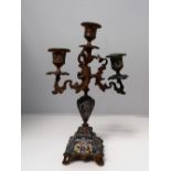 A gilt metal and champleve enamel decorated twin branch candleabra, with scrolling leaf supports,
