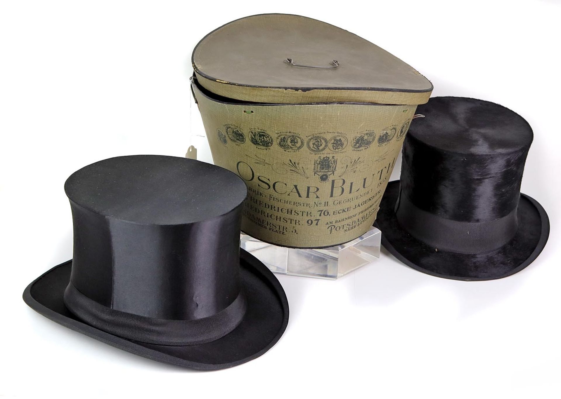 2 Zylinder im Karton um 1910Chapeau Claques aus schwarzem Satin mit Ripsband, innen schwarz