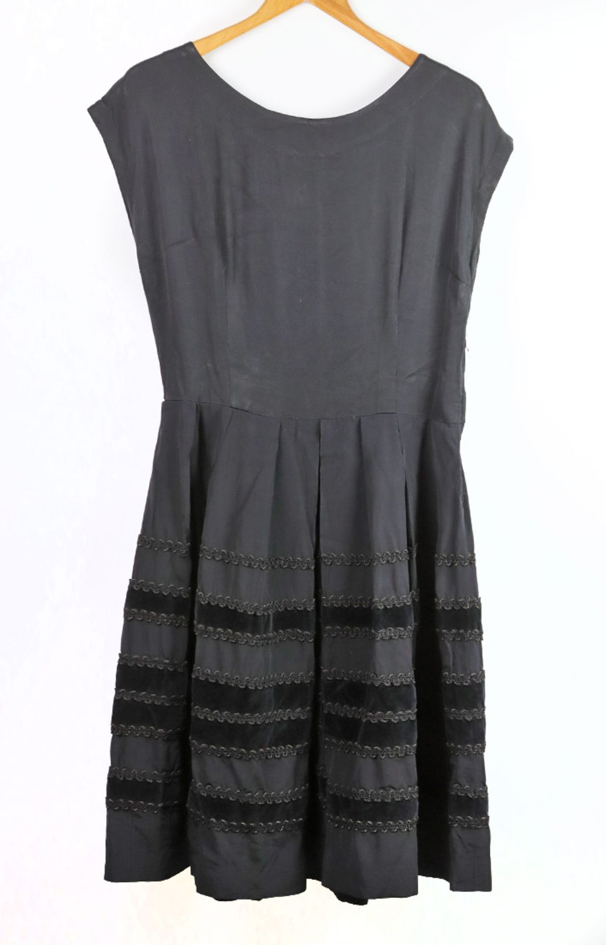 schwarze Damengarderobe um 1930dabei Kleid mit schmal geschnittenem, schulterbedecktem Oberteil,