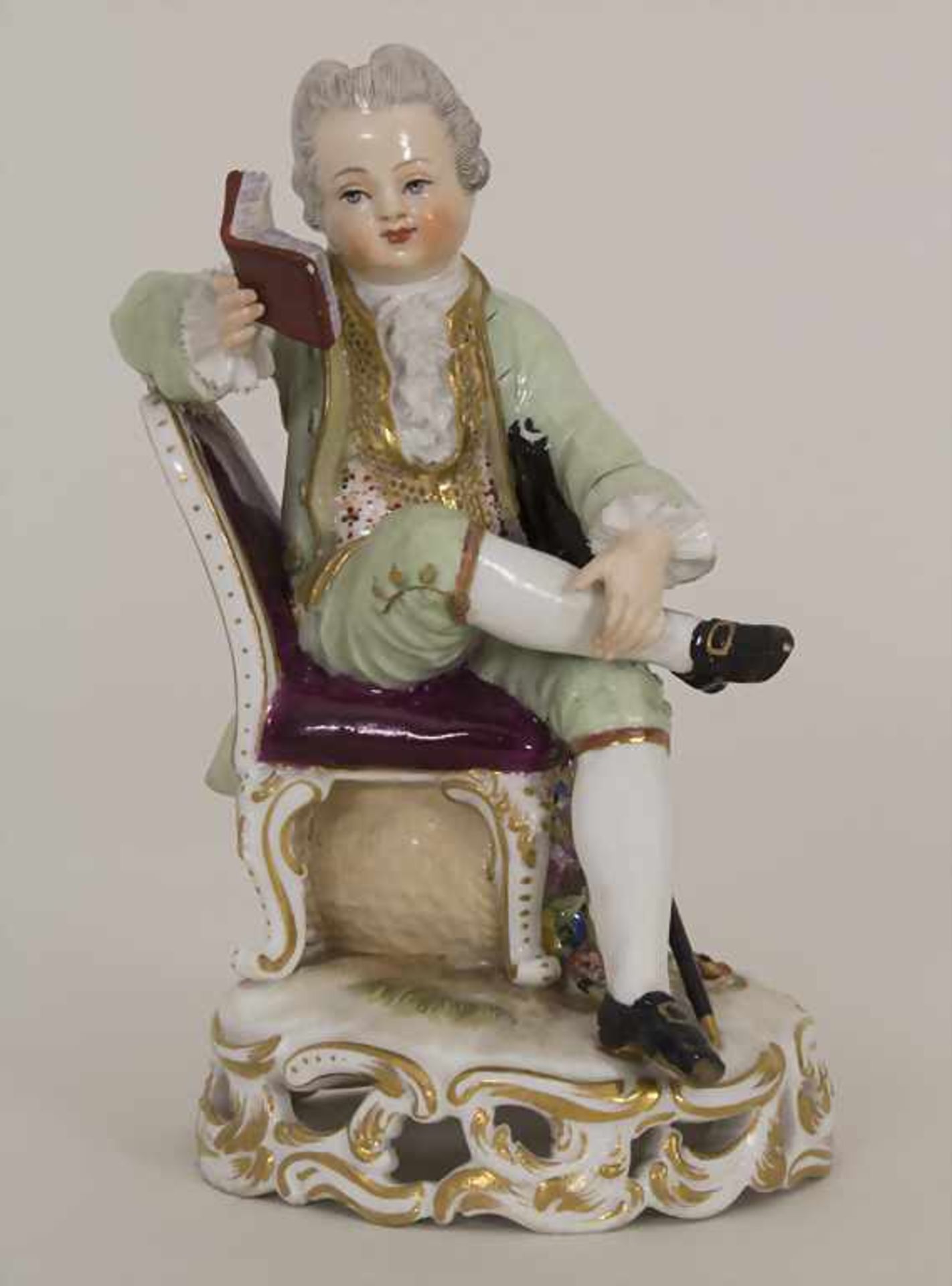 Kinderfigur 'Lesender Knabe mit Dreispitz und Säbel' / A reading boy with a three-cornered hat and a