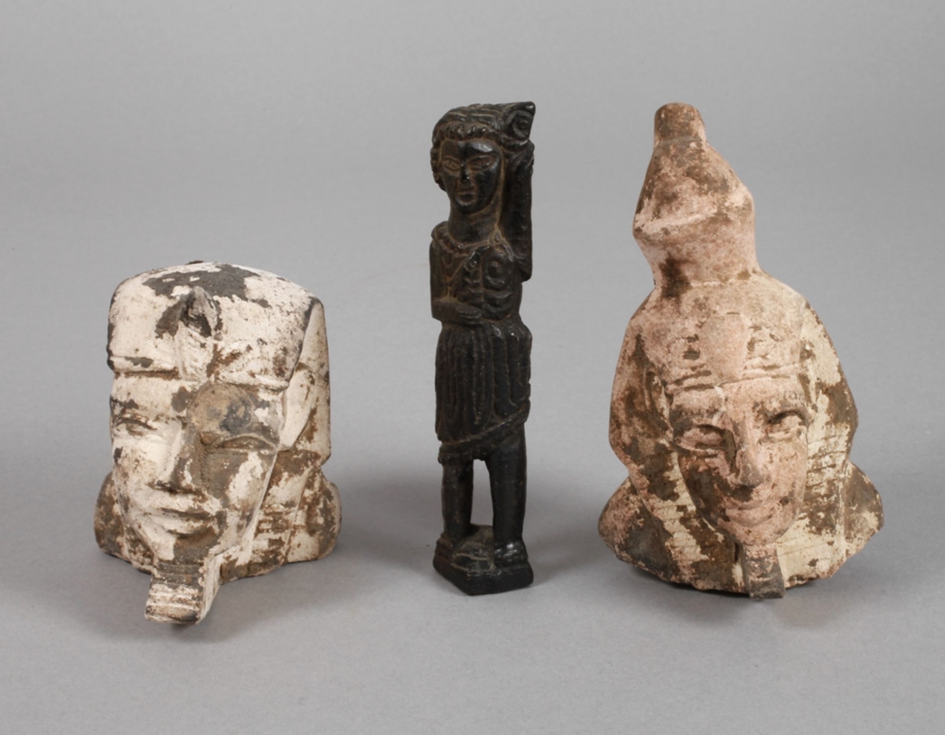 Drei Teile Ägyptenzwei Pharaonenköpfe, 20. Jh., Steinguss, Witterungsspuren, H ca. 14 und 9,5 cm,