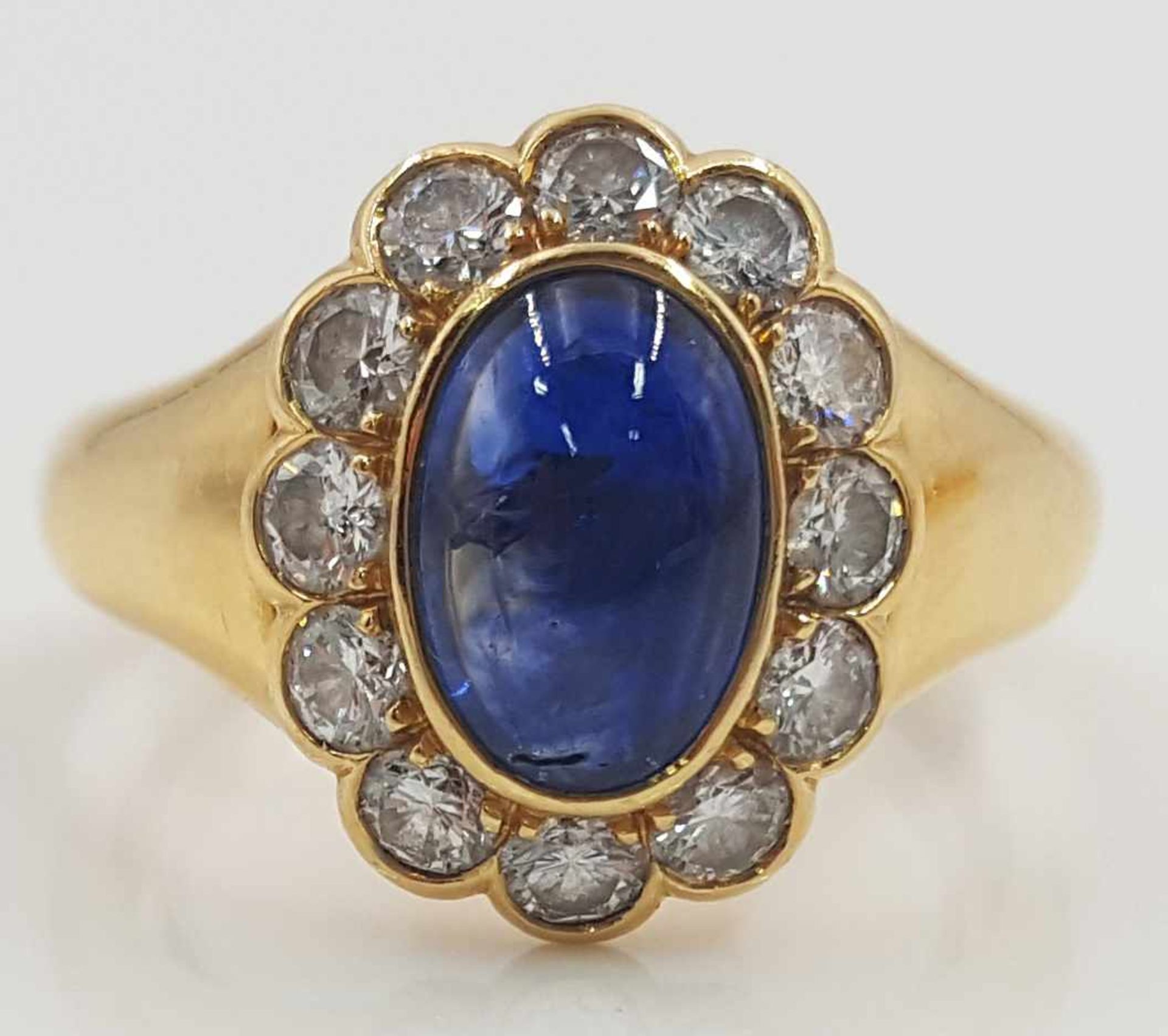 Yellow gold 750 ring with a Sapphire cabochon framed by 12 diamonds.
