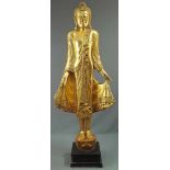 Standing Buddha. Carved wood. Gold colored with glass highlights.