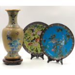 A vase on a carved wooden base with two plates. Cloisonné.A vase on a carved wooden base with ...