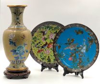 A vase on a carved wooden base with two plates. Cloisonné.A vase on a carved wooden base with ...