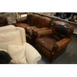 An early 20th century three-piece suite well-used, the brown leather covers with patina of age