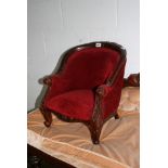 A Victorian-style child's chair, the carved scrolling frame on cabriole legs upholstered in red