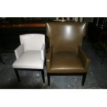 A modern desk chair covered in a grey stitched leather on a black frame and tapering legs. FOR