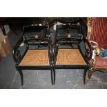 A pair of Regency armchairs with ebonized frames and gilt embellishments, cane seats on sabre legs