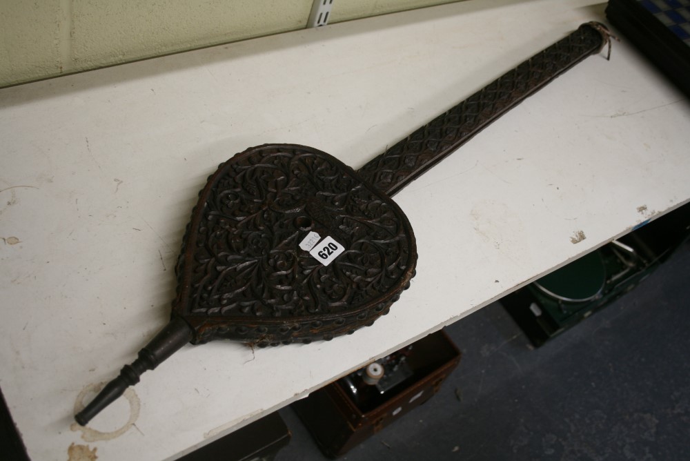 An Indian long-handled wooden bellows, circa 1900, carved overall with a peacock amongst scrolling