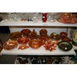 A shelf of various iridescent peach carnival glass, including baskets, rose bowls, fruit bowls,