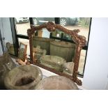 An early 20th century overmantel mirror with a shaped rectangular bevelled glass in an ornate
