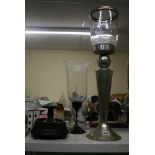 A modern tall candlestick in hammered white metal with hurricane shade, a smaller candlestick with