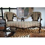 An ornate Victorian mahogany sofa, the twin shield shaped ends with downswept arms onto a