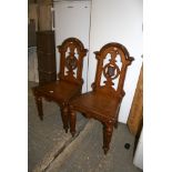 A pair of mid-Victorian oak hall chairs with cross-banded seats, the pierced dome-top backs each