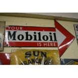An enamel sign advertising Mobil Oil in red and white, arrow shaped saying 'Your Mobil Oil is here',
