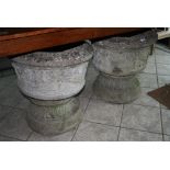 A pair of circular garden urns with swag and ribbon decoration, on socle bases [under table in hall]