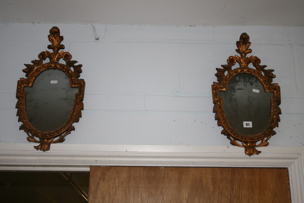 A pair of small Italianate shield-shaped mirrors with feather surmounts and carved frames. FOR