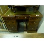 A Victorian mahogany desk of break-front form and nine drawers with a green leather inset top. FOR