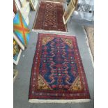 Two Eastern rugs, one in colours on a navy ground, the other with linked lozenges in dark tones [