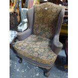 A Victorian wingback armchair in the Georgian style with bold carved cabriole legs on claw and