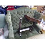 A high and wing-backed settee in the Georgian style in buttoned green velvet on moulded legs, and