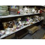 Three shelves of mixed kitchen and table wares including mugs, part dinner services, toast racks,