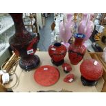 A collection of Oriental red lacquer items including a table lamp and shade, two vases, a ball on