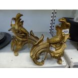 A pair of late 19th century French ormolu chenets in Louis XV style, each with a macaw perched