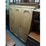 A Victorian polished pine wardrobe enclosed by three panelled doors. FOR DETAILS OF ONLINE BIDDING