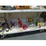 A shelf of glass ware including an amber Dartington glass bowl, a cranberry basket, a Caithness