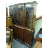 A mahogany reproduction break-front display bookcase behind astragal glazed doors on a cupboard