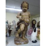 A life-size carved wood figure of a putto holding fruit, probably Flemish circa 1700, with