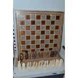 An Eastern chess board inlaid in wood, mother-of-pearl and bone, together with a bone chess set [