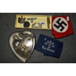 Four Nazi cap badges, two Nazi armbands and a reproduction shield shaped badge.