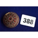 A Bohemian garnet circular pill box, late 19th century, in gilt metal pave-set with faceted