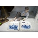 A Royal Copenhagen figure of a reclining boy eating, and two small square dishes [S] TO BID ON