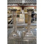 A pair of Edwardian filled silver table candlesticks, Corinthian columnar on gadrooned square bases,
