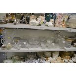 A shelf of glassware including rose bowls, vases, dessert bowls, four decanters and stoppers