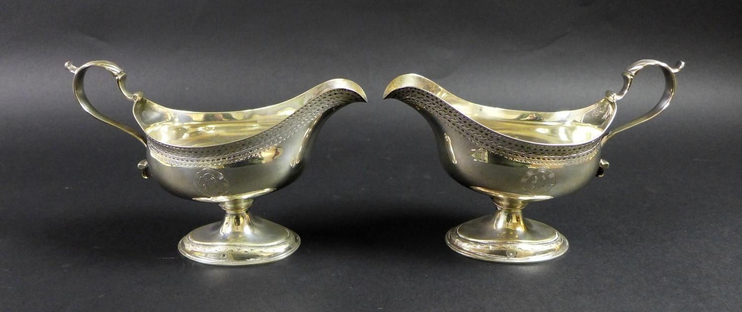 A pair of George III silver pedestal sauce boats, with bright cut decoration and engraved with the