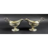 A pair of George III silver pedestal sauce boats, with bright cut decoration and engraved with the