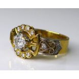 An 18ct gold and diamond ring of ornate buckle design, the central brilliant cut diamond of