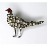 A paste set brooch in the form of a pheasant, with white metal legs and beak, red stone forming