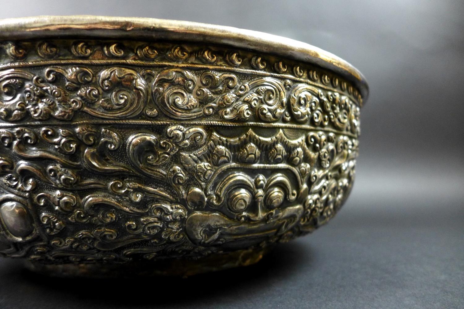 A late 19th century Thai silver large bowl, repousse decorated in relief with three face masks and - Image 5 of 10