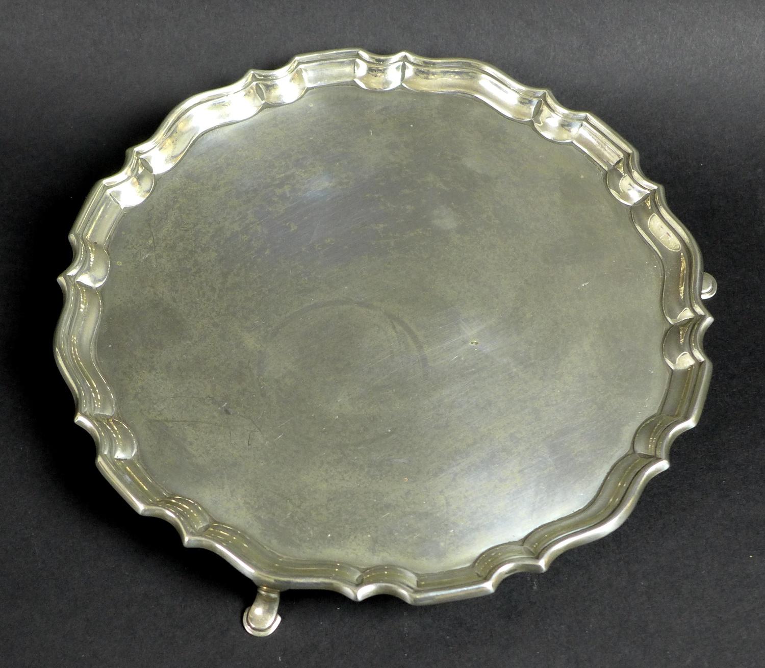 A George V silver tray, of circular form with Chippendale pie crust edge, raised on three feet,