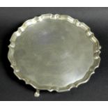A George V silver tray, of circular form with Chippendale pie crust edge, raised on three feet,