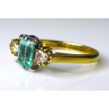 An 18ct gold, emerald and diamond ring, the central emerald cut stone of peppermint green colour and