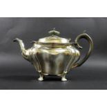 An Edward VII silver teapot, of Rococo bombe form, with ebonised finial and handle, raised on four