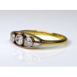A 9ct gold three stone diamond ring, central brilliant cut diamond approximately 0.06ct, each of the